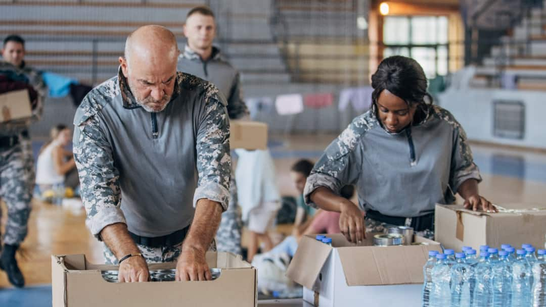 Image of a man and woman in military uniforms packing boxes