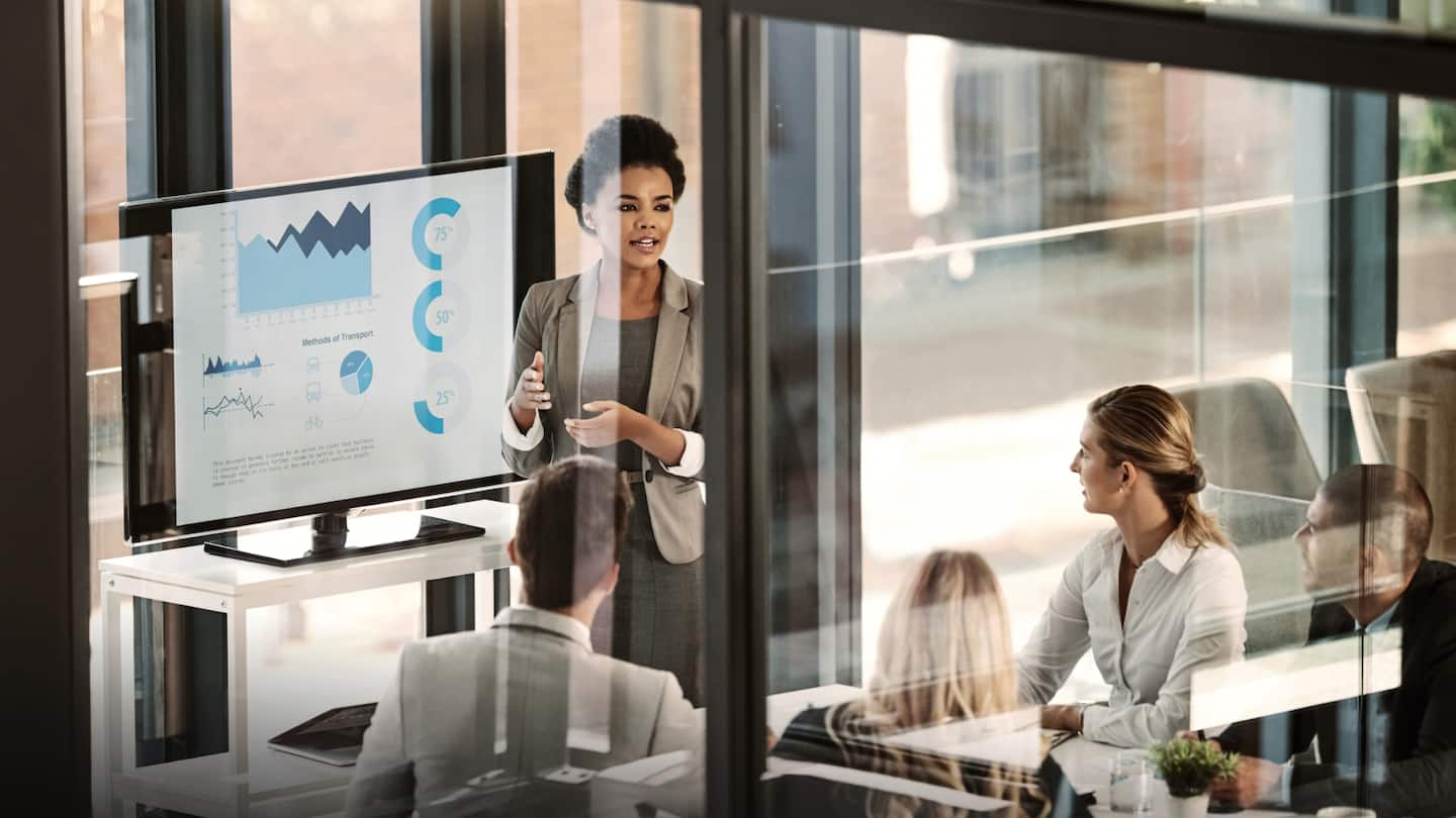 Image of five people in a business meeting discussing the on-screen presentation of chart data.